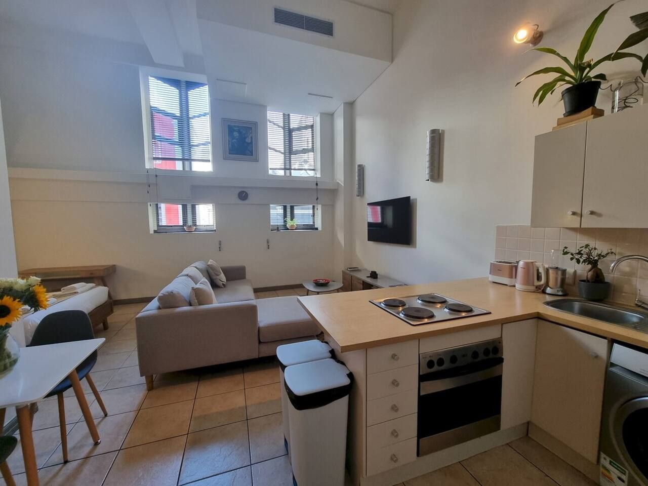A compact living space with a kitchenette, a sofa, a dining table, and a small kitchen island.