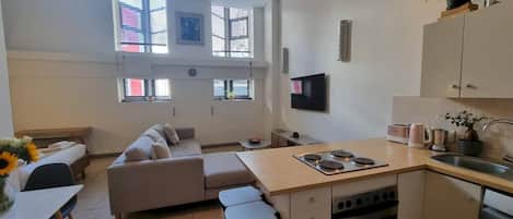 A compact living space with a kitchenette, a sofa, a dining table, and a small kitchen island.