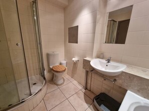 Un bagno con doccia vetro, water con sedile in legno, lavandino e specchio.