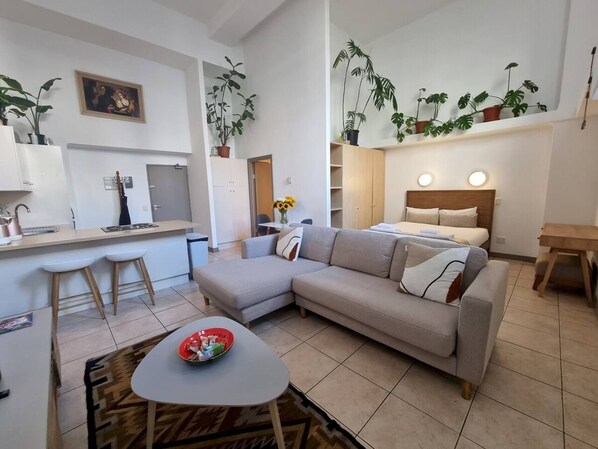 A modern living space with a sofa, dining area, and kitchen.