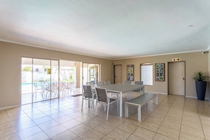 A spacious room with a large dining table, chairs, a bench, and a potted plant.