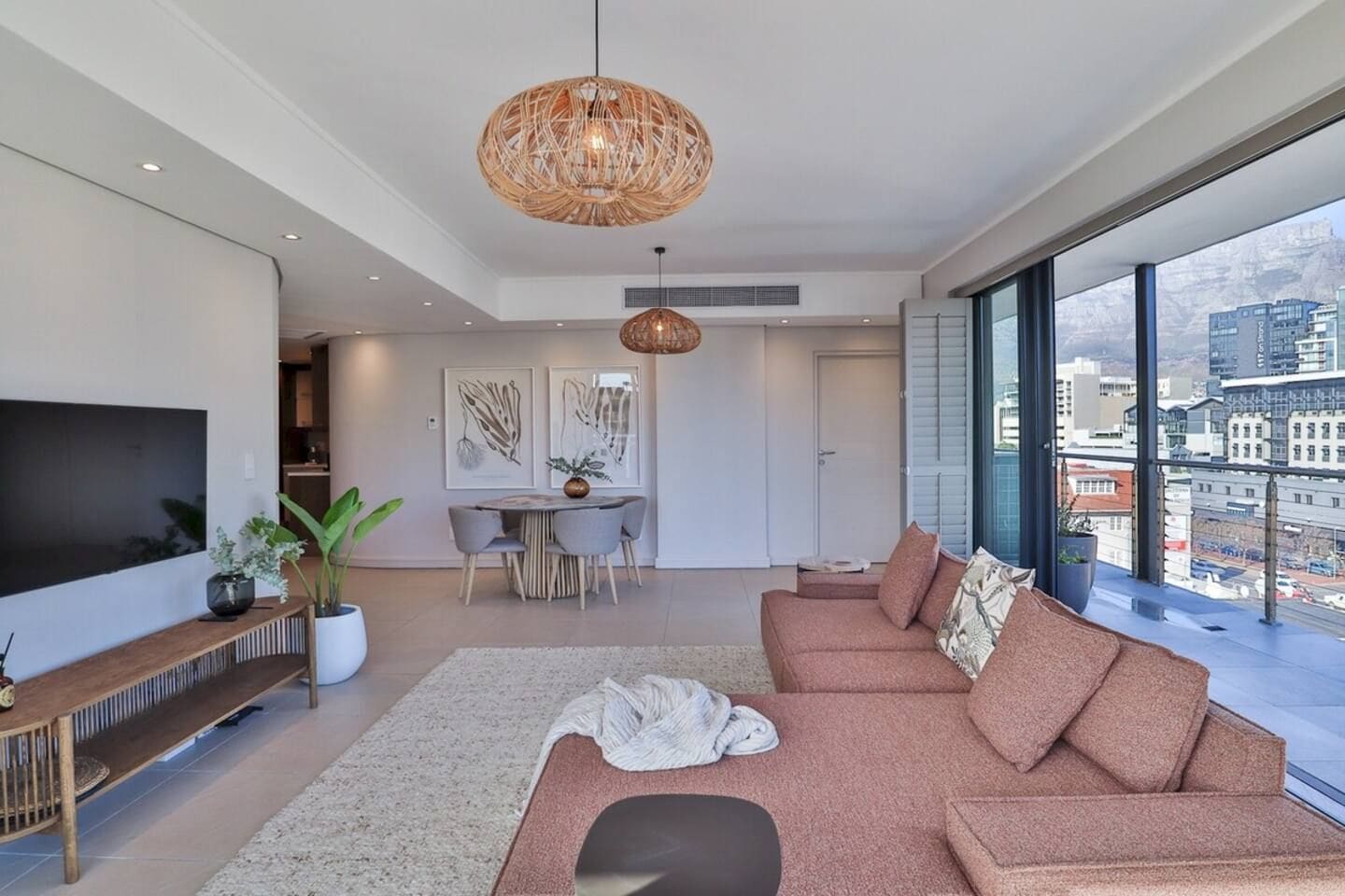 A modern living room with a large sofa, a dining table, and a TV.