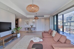 A modern living room with a large sofa, a dining table, and a TV.