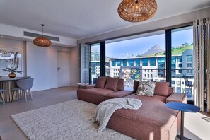 A modern living room with a large window, a sofa, a small table, and a decorative lamp.