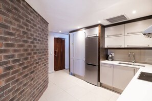 A modern kitchen with stainless steel appliances, white cabinetry, and a brick accent wall.