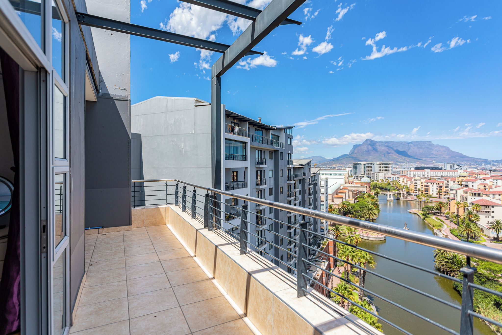 Un balcone con vista su un fiume e degli edifici, con una montagna sullo sfondo.