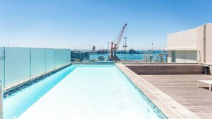 Ein Pool auf dem Dach mit freiem Blick auf den Hafen und die dahinterliegenden Kräne.