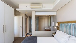Ein Hotelzimmer mit Bett, Bad und einem Flur, der zu einem weiteren Raum führt.
