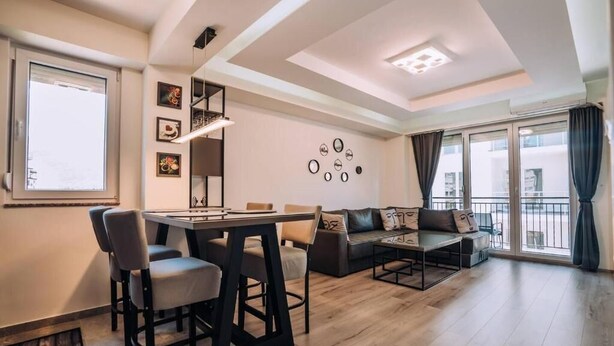 Una sala de estar moderna con comedor, sofá y balcón con cortinas.