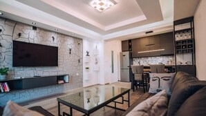 Una sala de estar moderna con un televisor de pantalla plana, una mesa de centro de vidrio y un sofá de cuero.