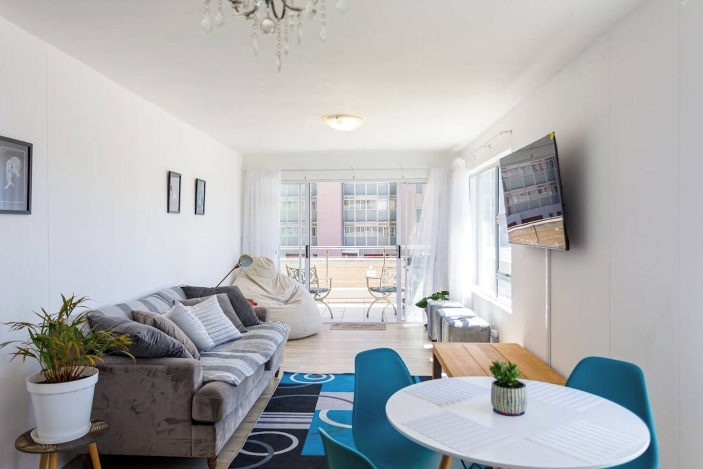 A modern living room with a sofa, a coffee table, and a TV mounted on the wall.