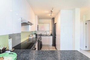 A modern kitchen with a black granite countertop, stainless steel appliances, and white cabinetry.