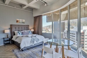 Una camera da letto moderna con un letto grande, un tavolino in vetro e vista sulla città.