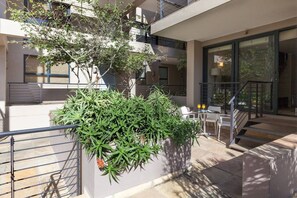Un espace extérieur aménagé avec une table et des chaises, un escalier et un pot de fleurs.