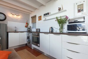 Une cuisine moderne avec des meubles blancs, des appareils en acier inoxydable, un four à micro-ondes et une horloge au mur.