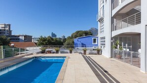 A rooftop swimming pool with a clear view of the city skyline, a blue building, and a white building with balconies. - Harbour Terrace 48 by Ctha (Cape Town)