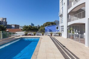 Una piscina sul tetto con vista chiara sullo skyline cittadino, un edificio blu e un edificio bianco con balconi.