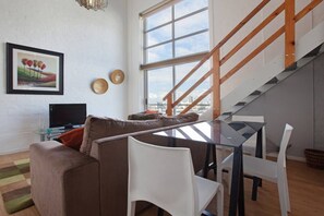 Un salon moderne avec un canapé, une table à manger en verre et un escalier.