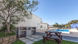 A rooftop pool area with a picnic table, a tree, and a building with a sign. - Harbour Terrace 48 by Ctha (Cape Town)