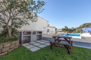 Area piscina sul tetto con tavolo da picnic, un albero e un edificio con un cartello.