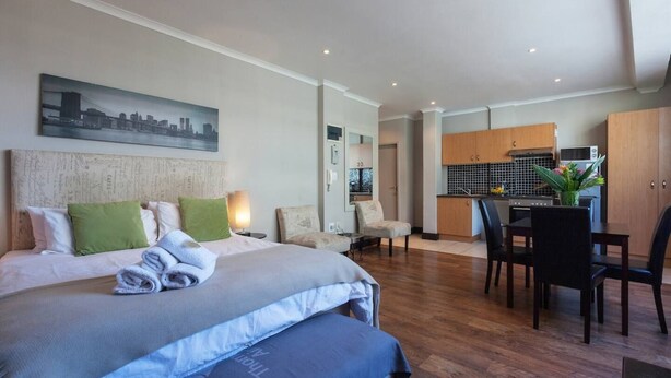 A hotel room with a bed, a desk, and a kitchenette. - City Studio | Parking, Pool & gym by ctha (Cape Town)