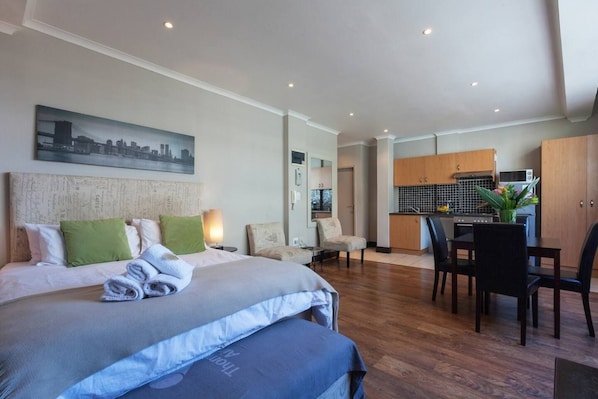 A hotel room with a bed, a desk, and a kitchenette.