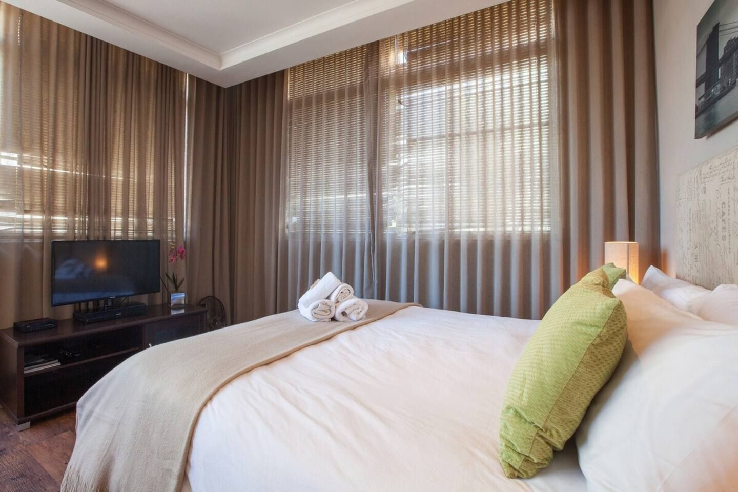 Ein Hotelzimmer mit einem großen Bett, einem Flachbildfernseher und Vorhängen.