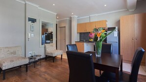 A modern living room with a dining table, two sofas, and a kitchen in the background. - City Studio | Parking, Pool & gym by ctha (Cape Town)