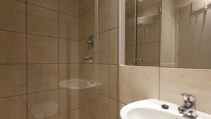 A bathroom with a shower, a sink, and a mirror. - City Studio | Parking, Pool & gym by ctha (Cape Town)