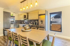A modern kitchen with a dining area, stainless steel appliances, and a large window.