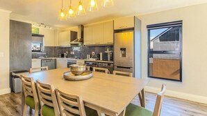 Una cocina moderna con una isla central, electrodomésticos de acero inoxidable e iluminación colgante.
