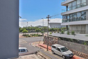A modern building with a parking area, a street with a roundabout, and a clear sky.