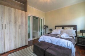 A bedroom with a bed, bedside tables, a wardrobe, and a sliding glass door leading to a bathroom.