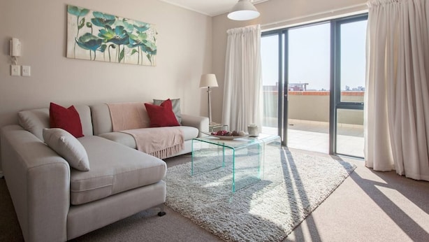 Una sala de estar moderna con un sofá, una mesa de centro de vidrio y un cuadro en la pared.