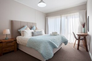 Una camera da letto con un letto, un comodino, una lampada e una scrivania con una sedia.