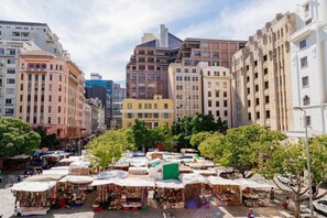 Een levendige openbare markt met verschillende kraampjes, omringd door meerlaagsgebouwen.