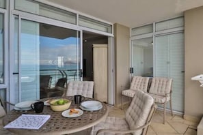 Un balcone con un tavolo apparecchiato per due, sedie e vista sul mare.