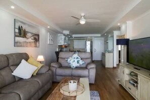 A living room with a sofa, armchair, coffee table, and a television.