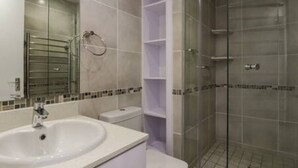 A bathroom with a sink, toilet, and glass shower enclosure. - Ocean View C403 by Ctha (Cape Town)