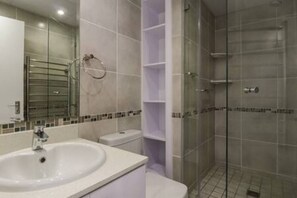 Un bagno con lavandino, wc e cabina doccia in vetro.