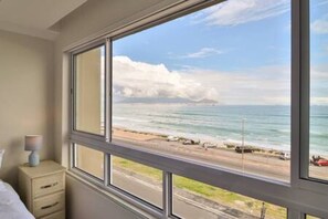 A room with a large window overlooking a beach.