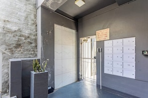 A hallway with a closed door, a mailbox, and a wall-mounted number plate.