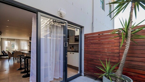 Una cocina moderna con una puerta corrediza de vidrio que da a un comedor con taburetes de bar.