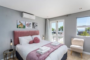 Una camera da letto moderna con un letto, una sedia, opere d'arte e una finestra.