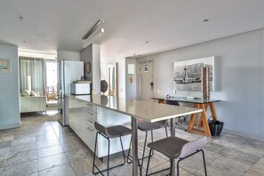 A modern kitchen with a central island, bar stools, and a dining area with a table and chairs.