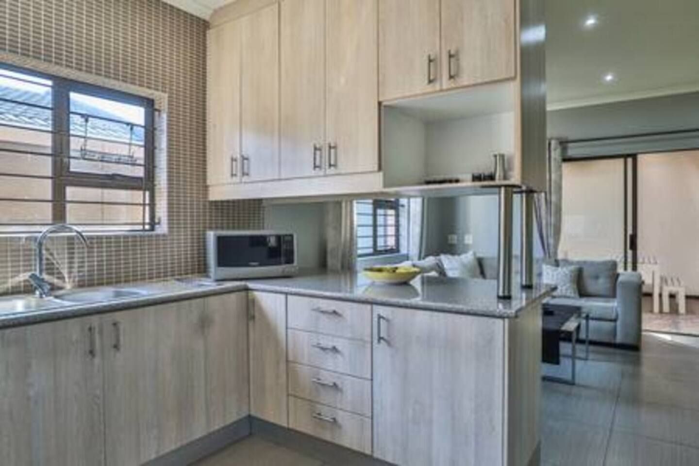 Una cocina moderna con armarios de madera clara, un microondas y un lavamanos.