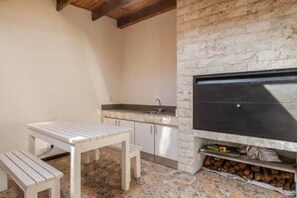 Una piccola cucina esterna con parete in pietra, lavello e barbecue.