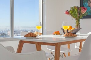 Colazione con croissant, succo d'arancia e una ciotola di frutta su un tavolo con vista sulla città.