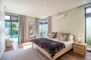 Un dormitorio moderno con una cama grande, una mesita de noche y vistas a una piscina.