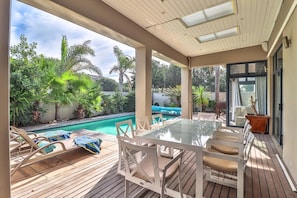 Un espacio al aire libre techado con piscina, terraza de madera y asientos.